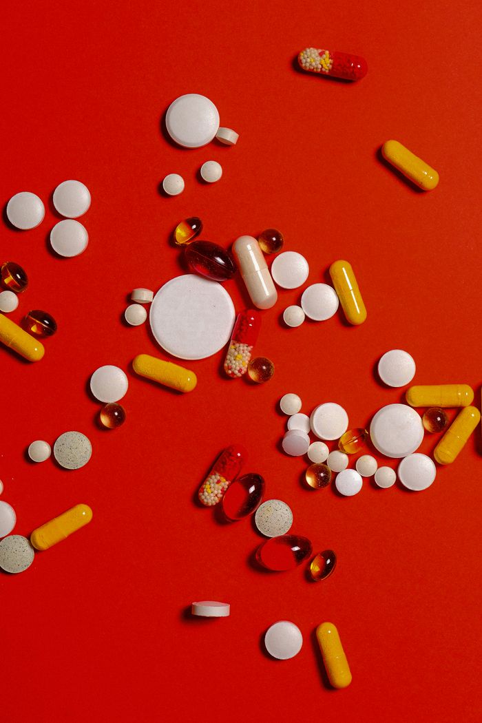 who-we-are A diverse array of pills and capsules scattered on a vibrant red surface.