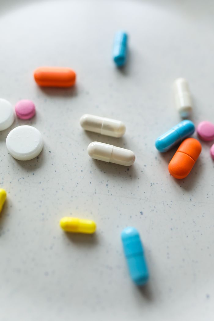 our-story A creative array of colorful pills and tablets spread on a surface, showcasing various pharmaceutical forms.